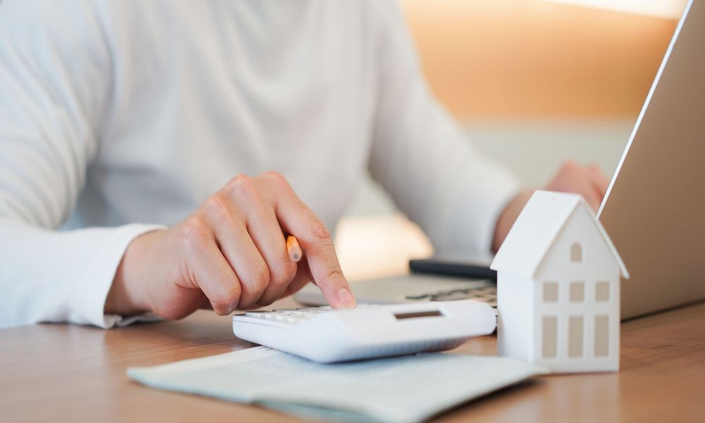 A person is calculating a house value